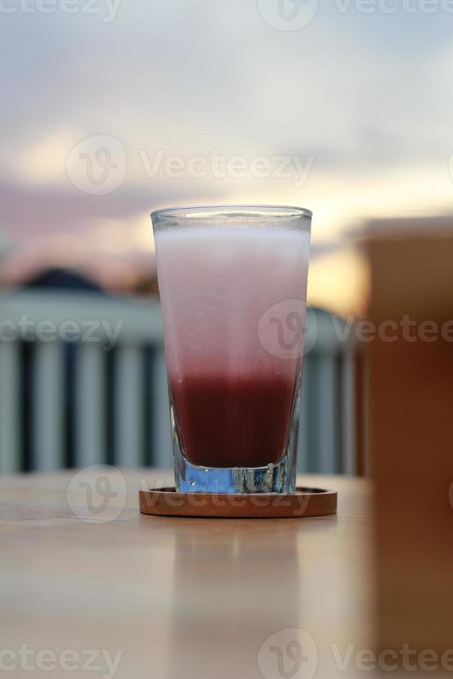 a glass of red velvet latte served cold on the table. photo