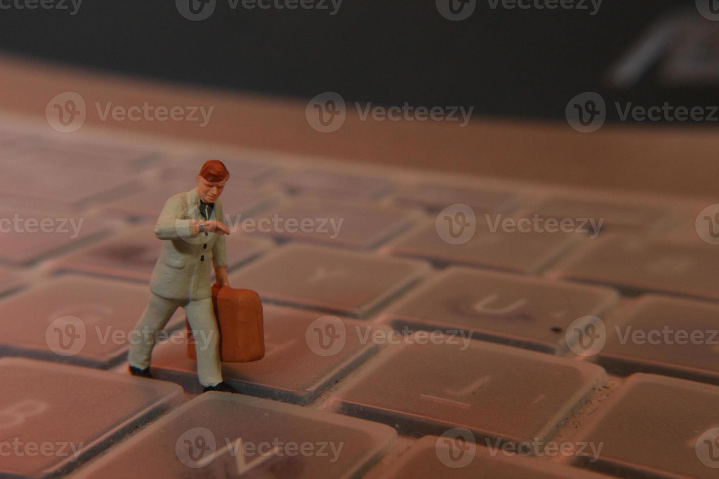 a miniature figure of an office worker carrying a briefcase walking between the keyboards. photo