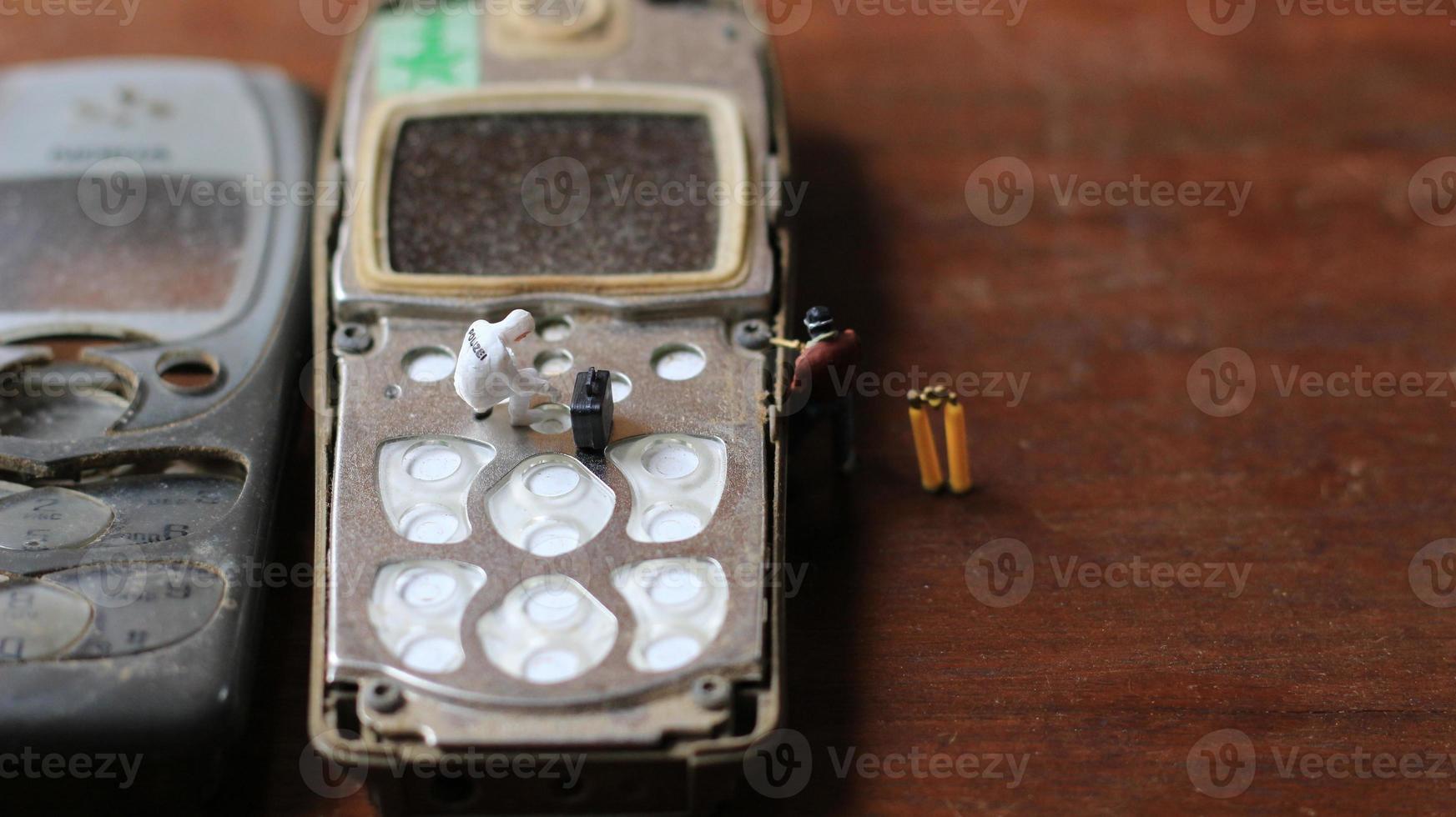 miniature figure of a technician repairing an old broken cell phone. working technician concept. photo