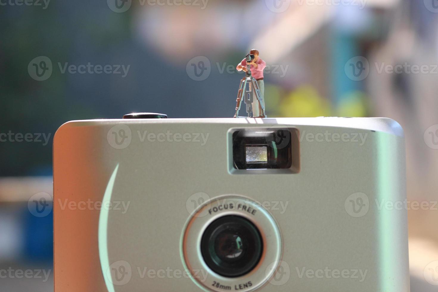 miniature figure of a videographer recording on an analog camera. photo