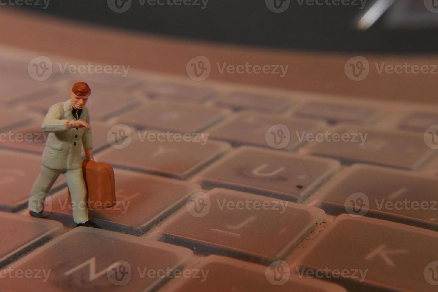 a miniature figure of an office worker carrying a briefcase walking between the keyboards. photo