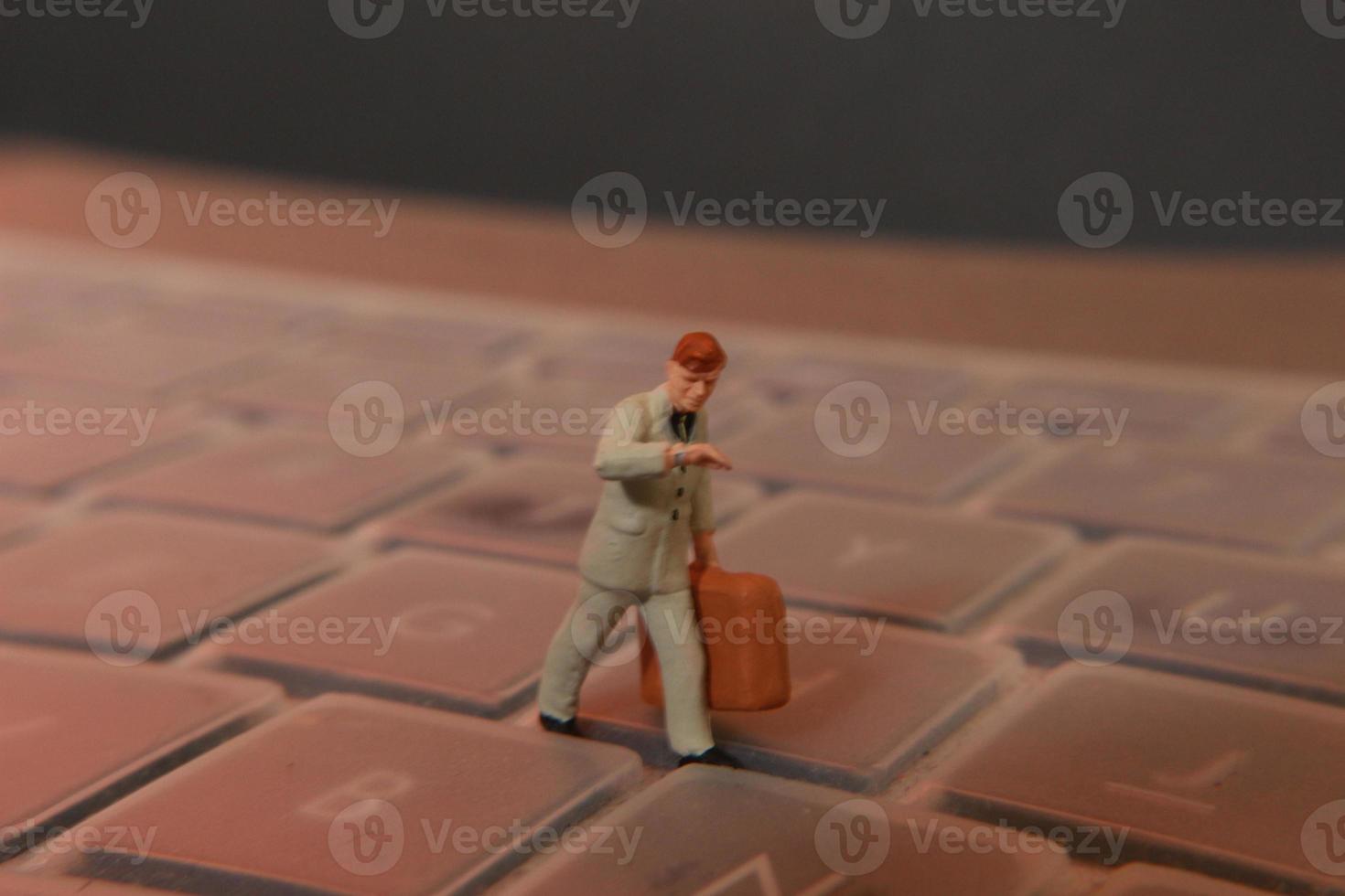 a miniature figure of an office worker carrying a briefcase walking between the keyboards. photo
