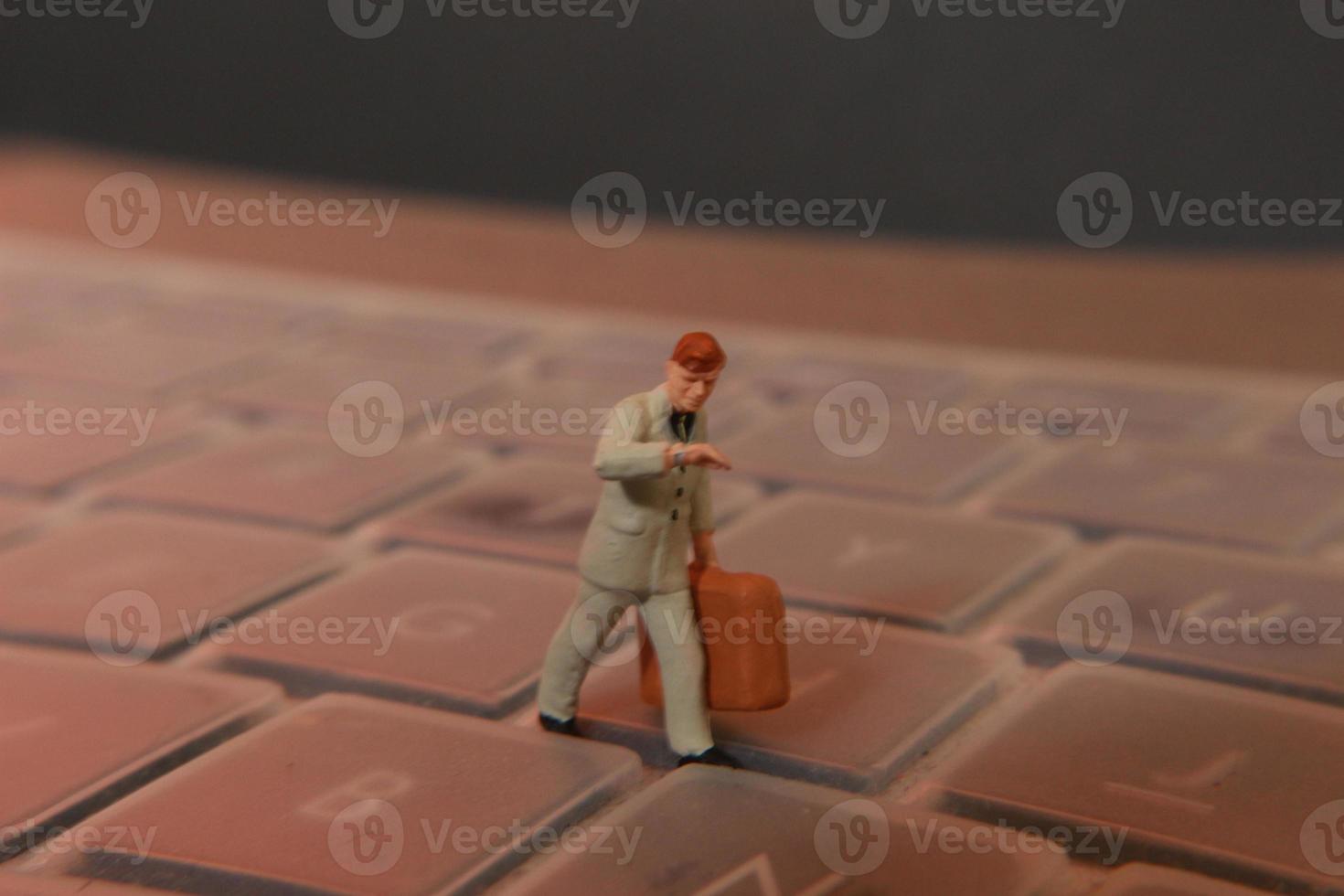 a miniature figure of an office worker carrying a briefcase walking between the keyboards. photo