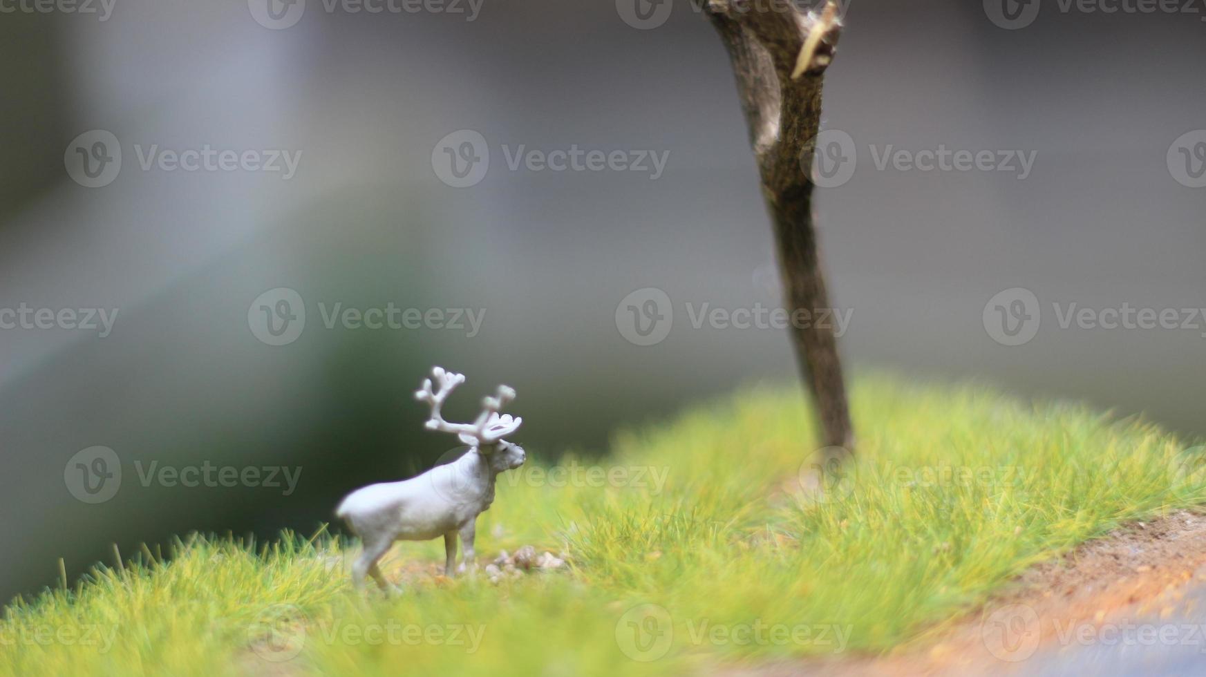 miniature figure of a moose eating. a meadow and tree diorama. concept of nature and animals. photo