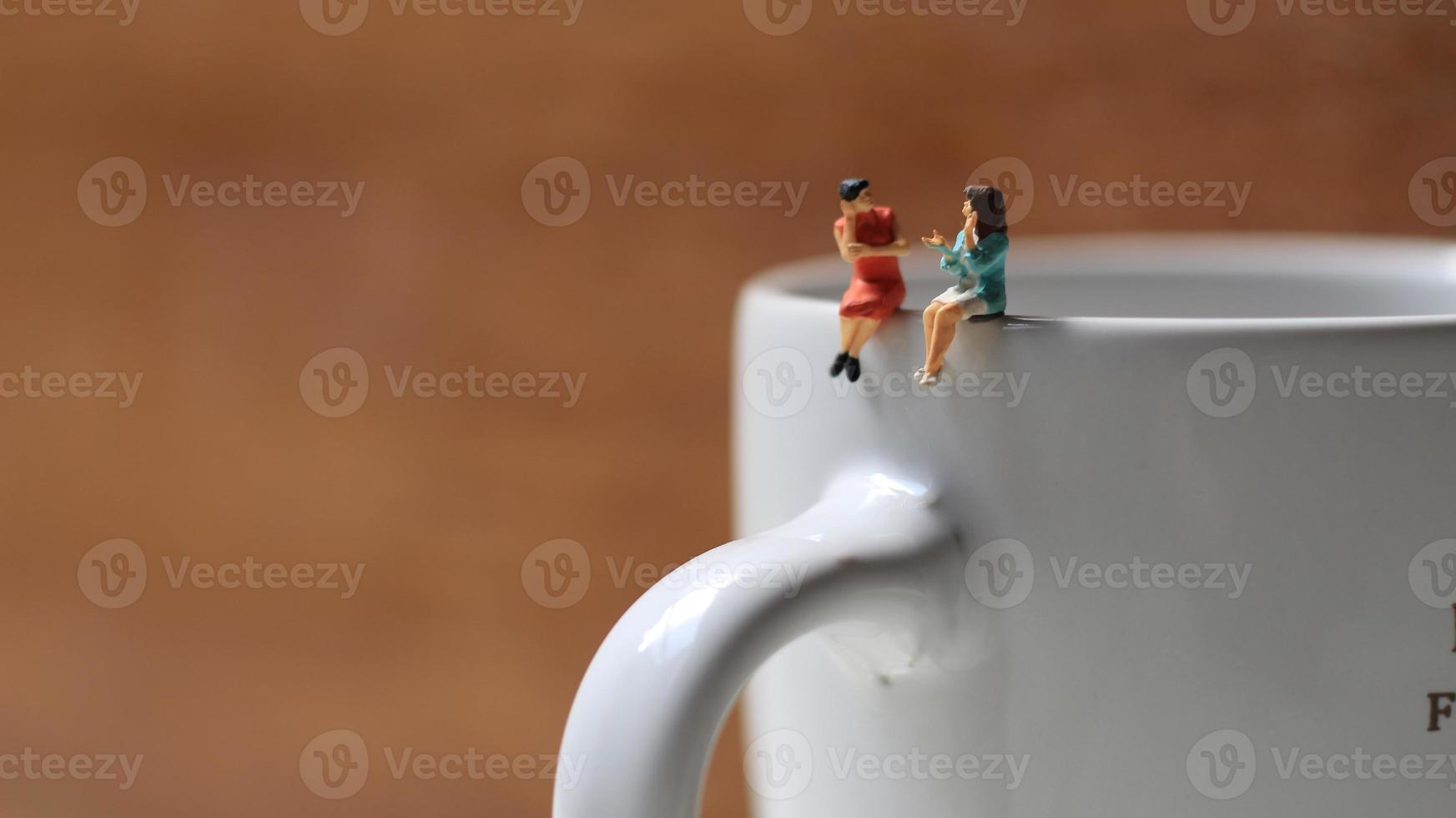 Miniature figures of 2 women talking over glasses. discussion concept. photo