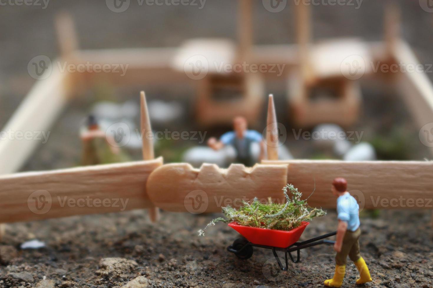 A close up of miniature figure of a goat herder feeding in a wooden cage. Shepherd concept. photo