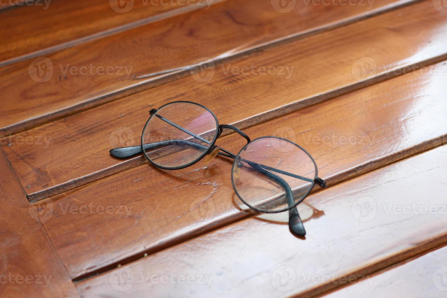 a close up of eyeglasses with black frames isolated natural patterned wooden background. photo