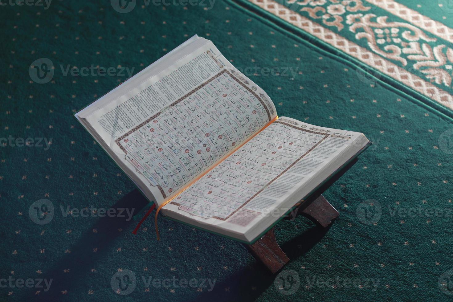 a close up of the holy book Al-Quran on a green prayer rug. Islamic photo concept.