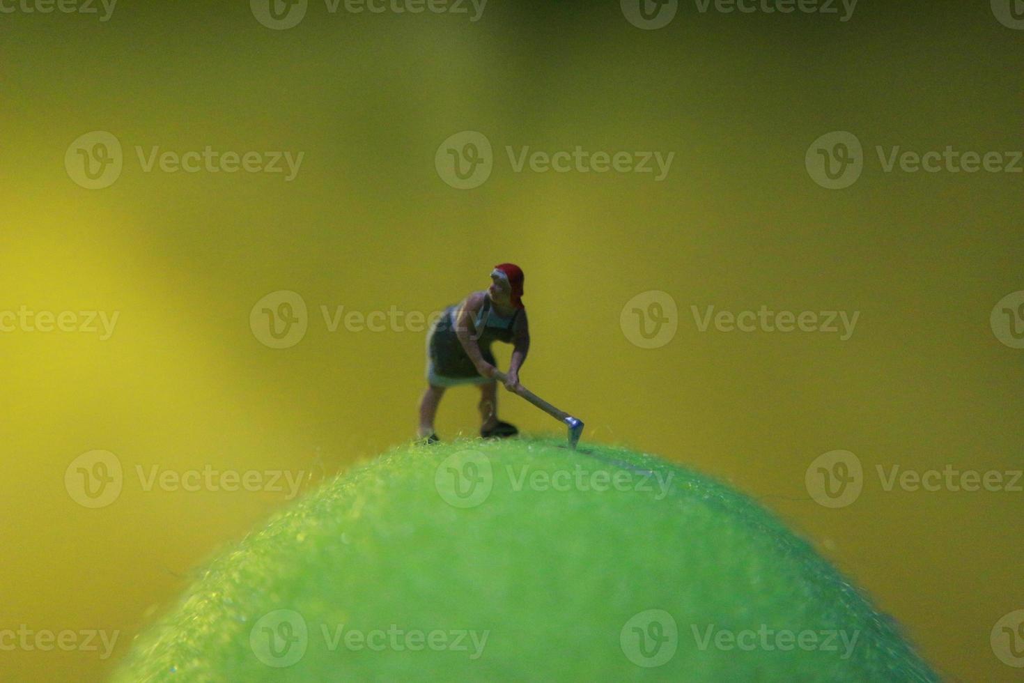 miniature figure of a female farmer working the land with a sunrise background. photo