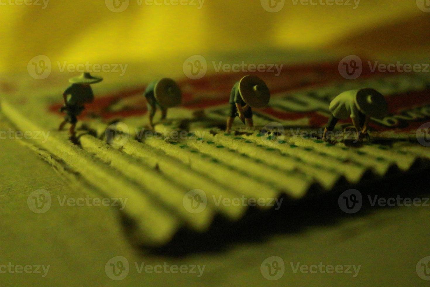 a close up of miniature figures of farmers who are farming on cardboard pieces like rice fields. farmer farming concept. photo