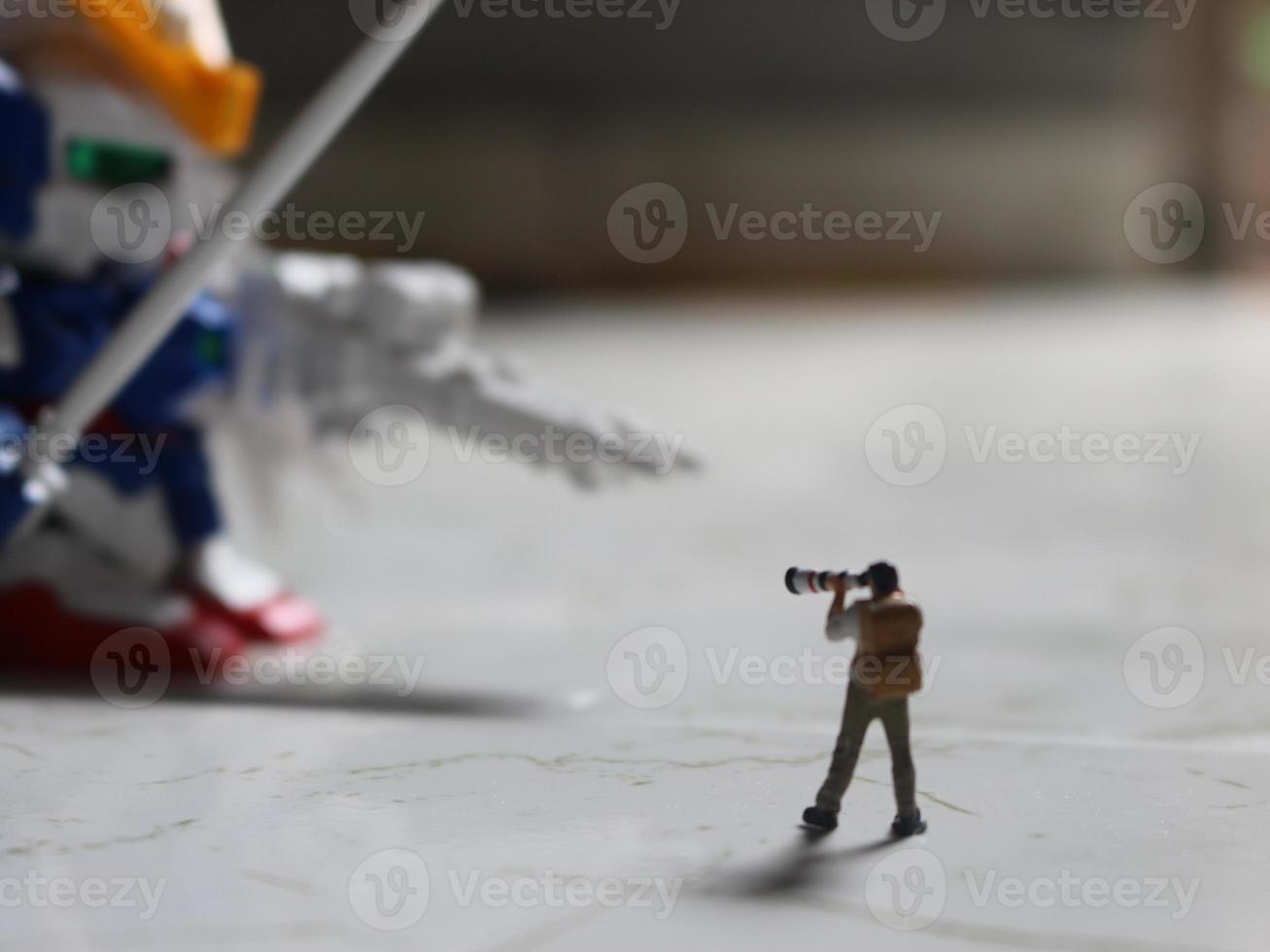 miniature figure of a photographer taking a photo of a robot.