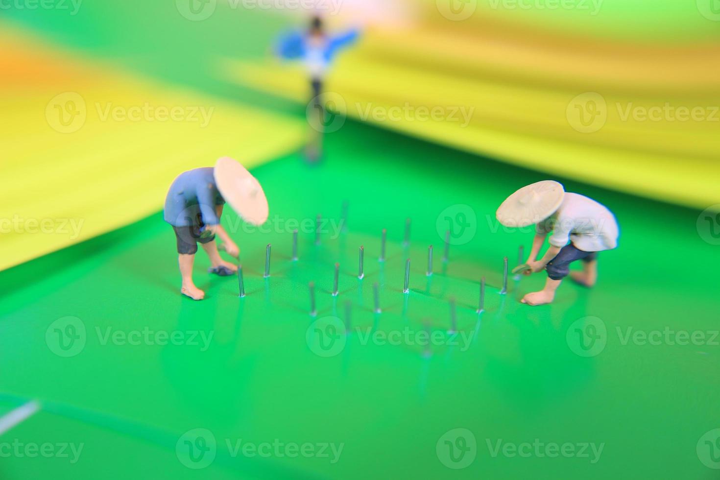 miniature figure of farmers growing crops in the form of staples on green paper. Concept of agriculture photo. photo