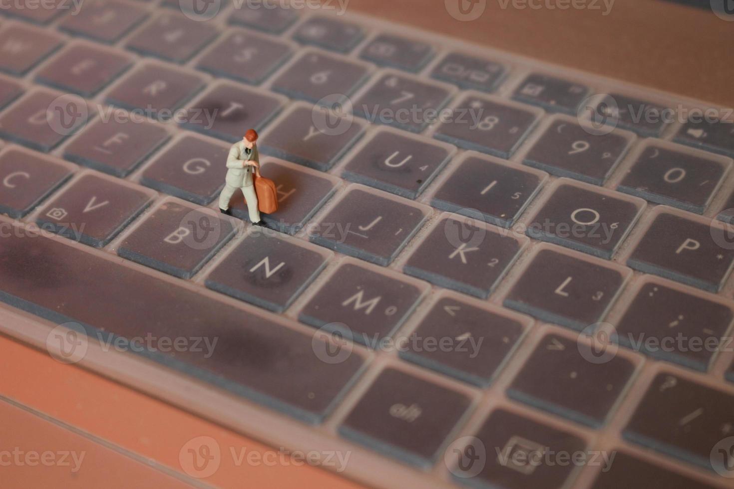 a miniature figure of an office worker carrying a briefcase walking between the keyboards. photo