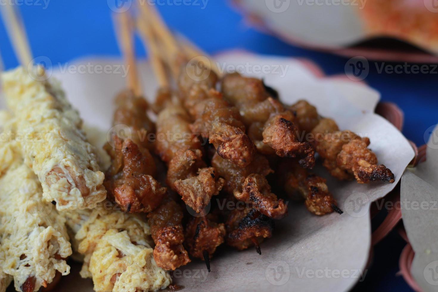 photo of chicken satay coated with fried egg and chicken intestine satay served with red chili sauce. Indonesian food called Sate Taichan. Food concept photo.