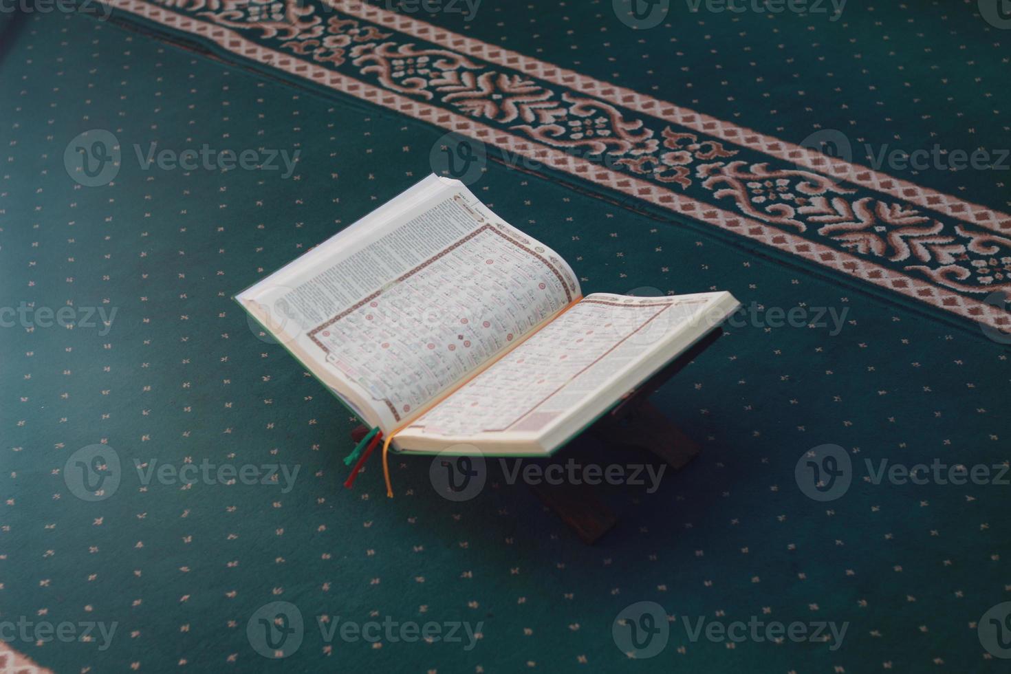 a close up of the holy book Al-Quran on a green prayer rug. Islamic photo concept.