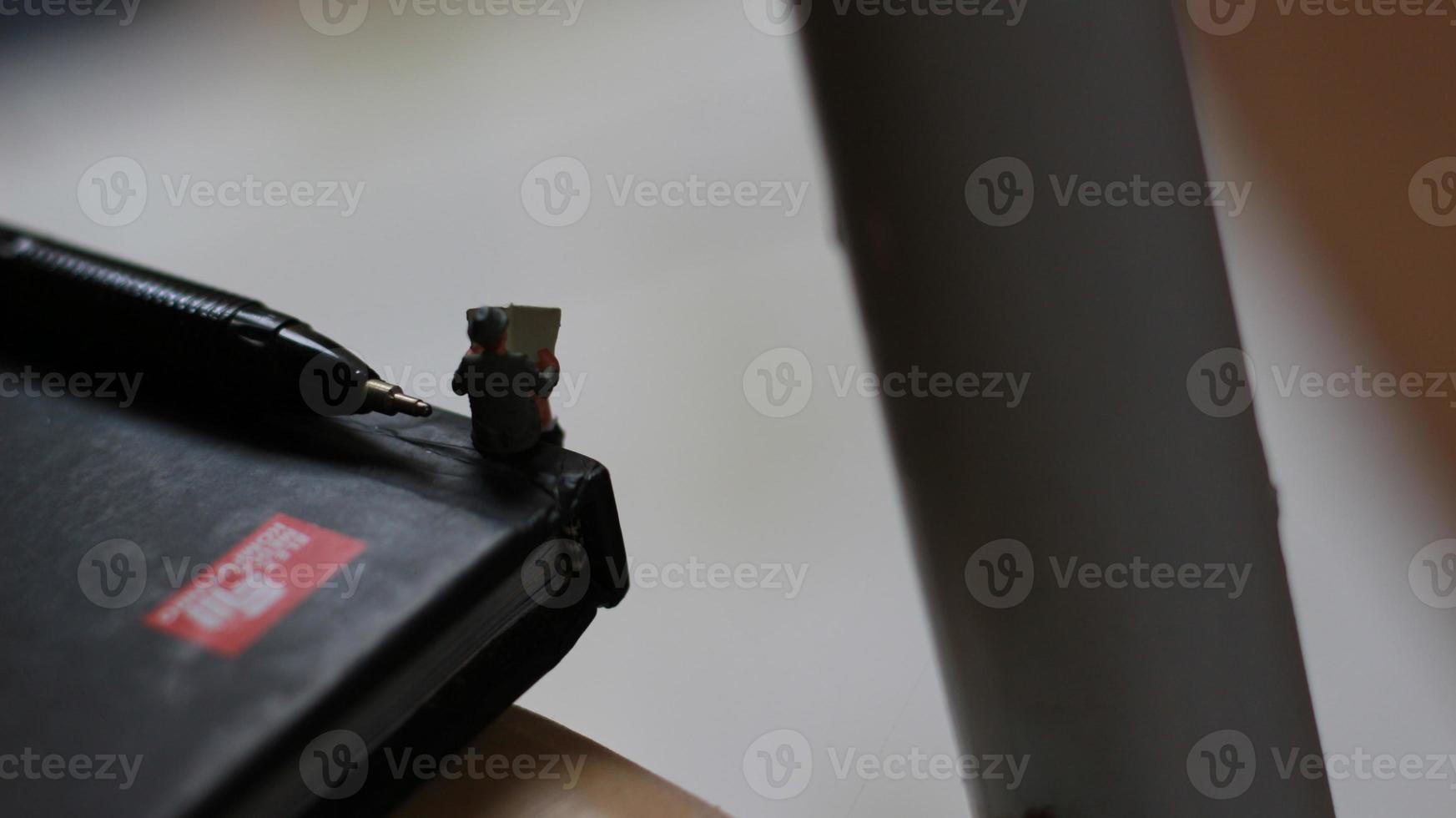 a view of miniature figure reading a newspaper on a book. photo