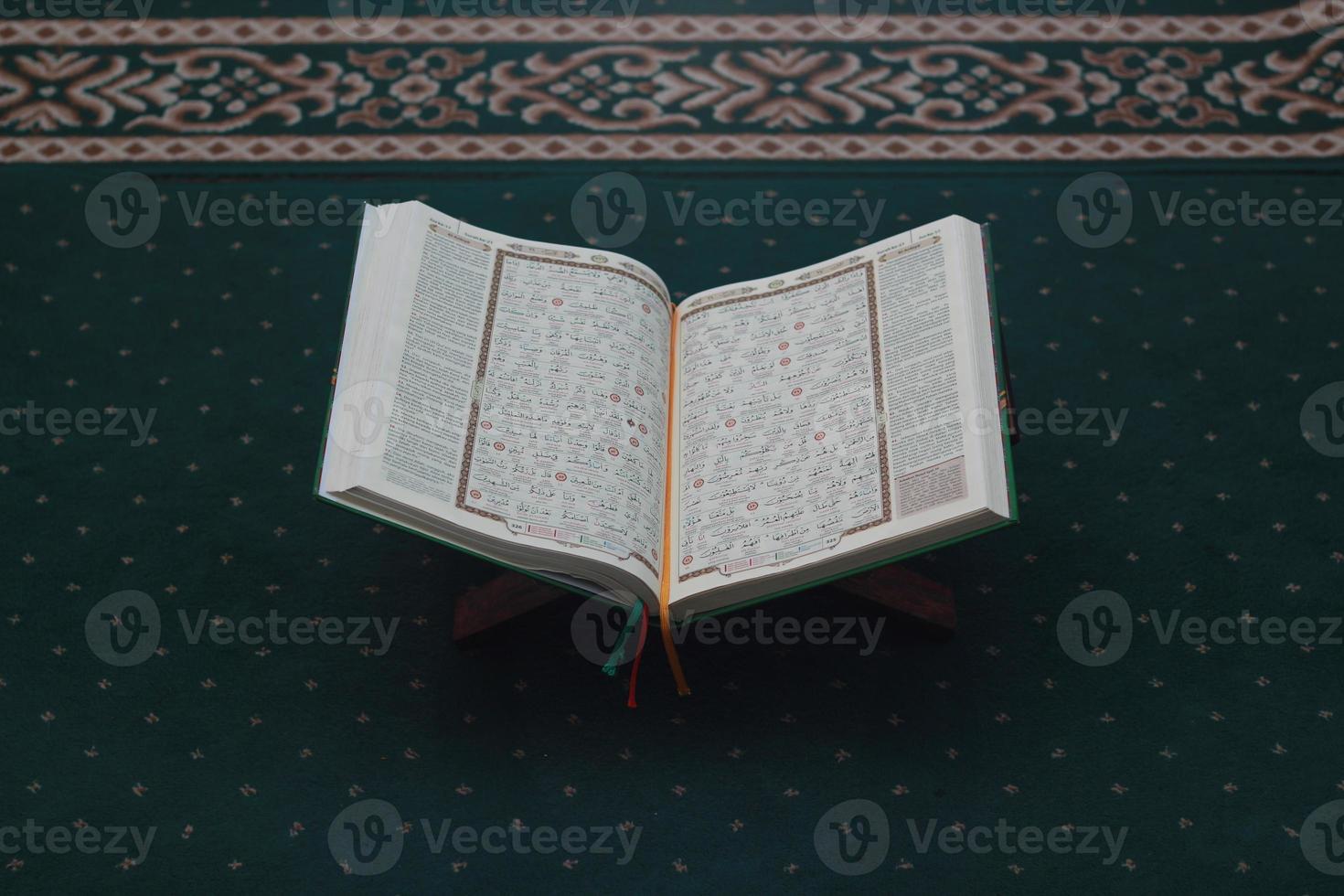 a close up of the holy book Al-Quran on a green prayer rug. Islamic photo concept.