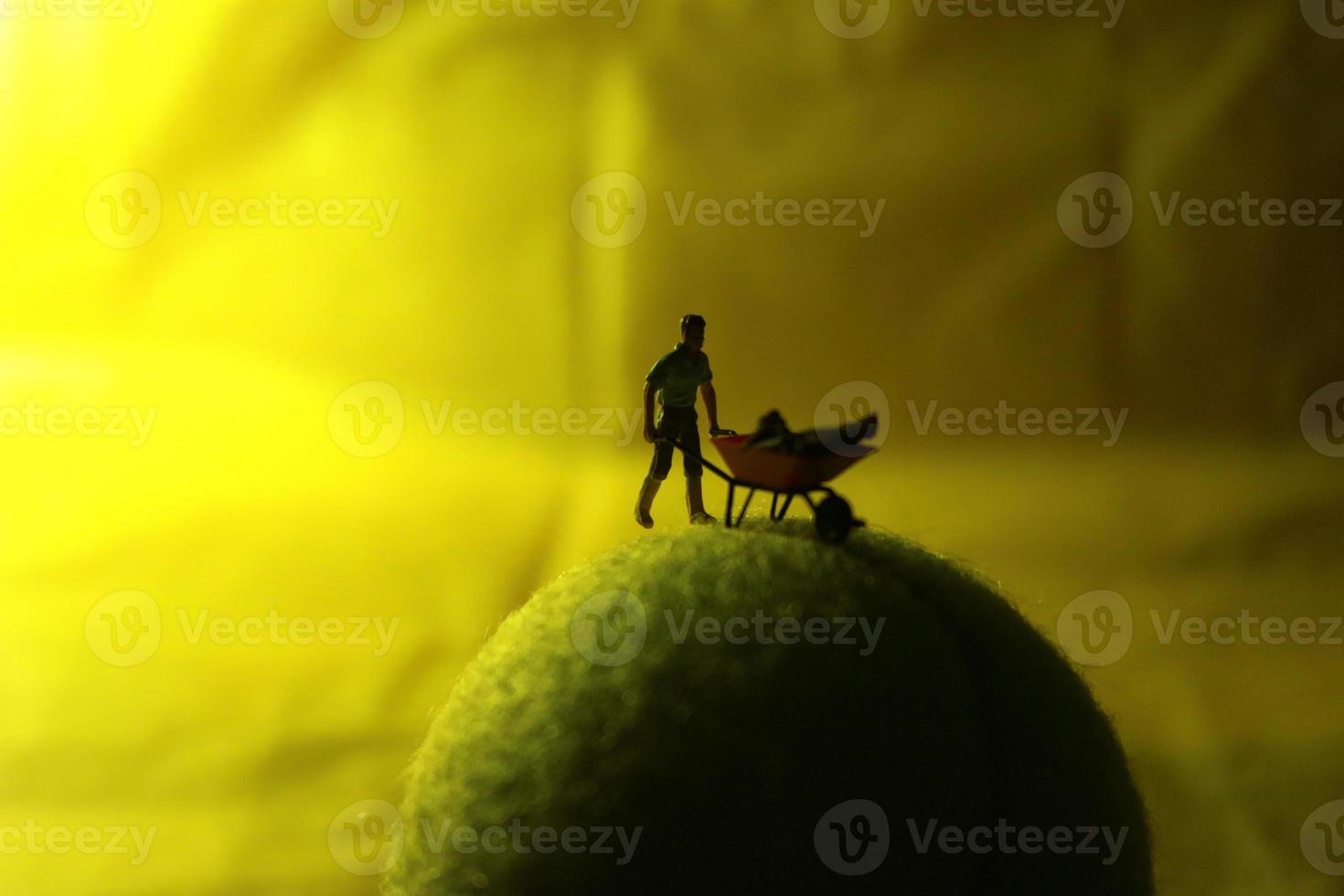 miniatura figura de un hembra granjero trabajando el tierra con un amanecer antecedentes. foto