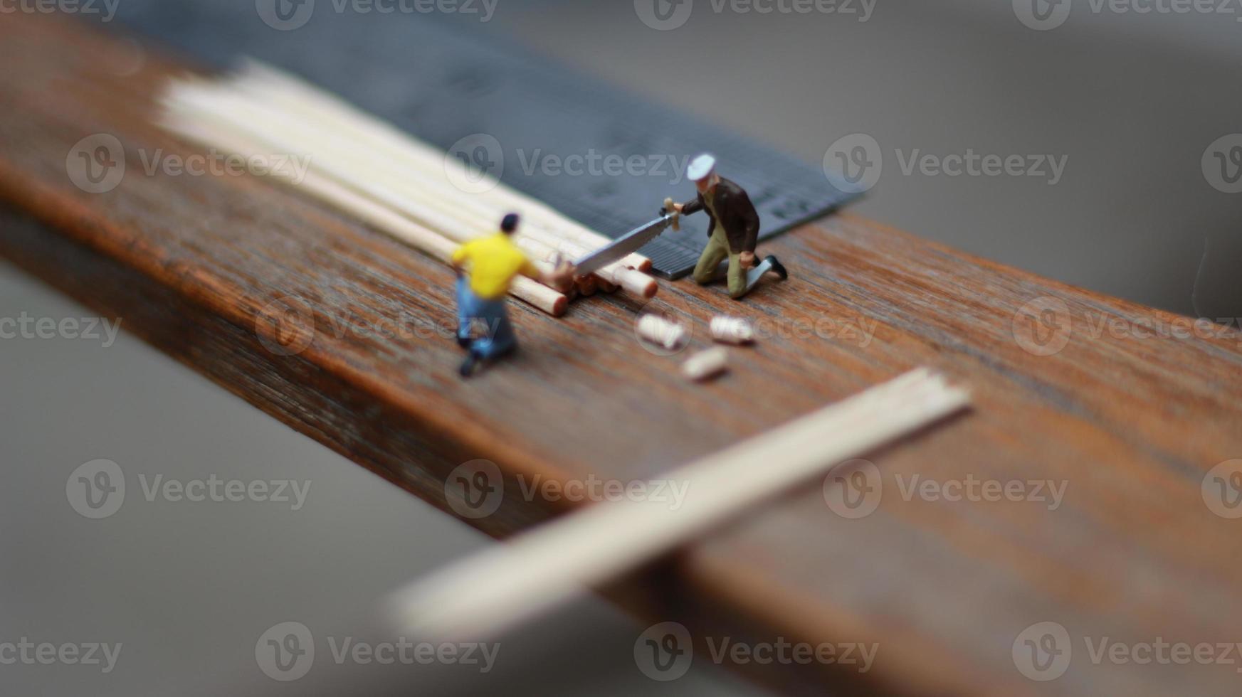 Miniature figure of a worker cutting toothpicks. carpenter activity photo concept.