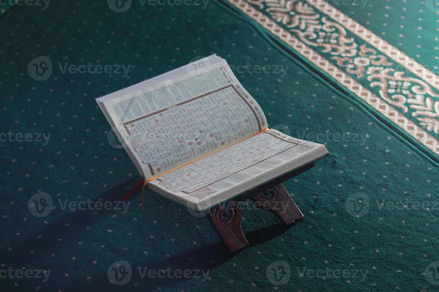 a close up of the holy book Al-Quran on a green prayer rug. Islamic photo concept.
