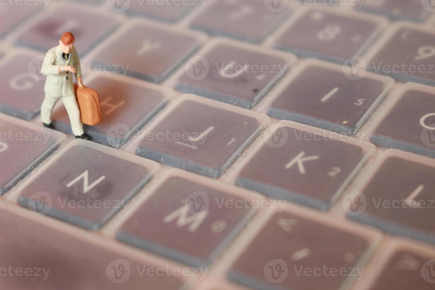 a miniature figure of an office worker carrying a briefcase walking between the keyboards. photo