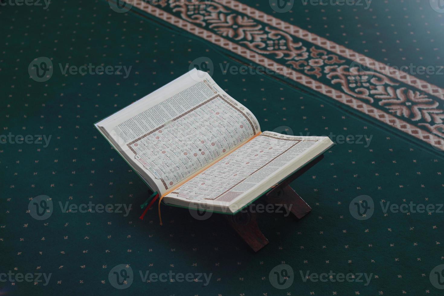 a close up of the holy book Al-Quran on a green prayer rug. Islamic photo concept.