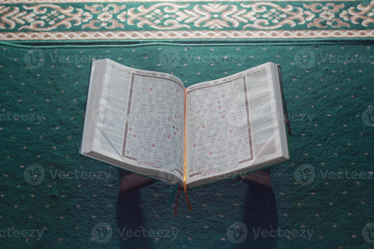 a close up of the holy book Al-Quran on a green prayer rug. Islamic photo concept.