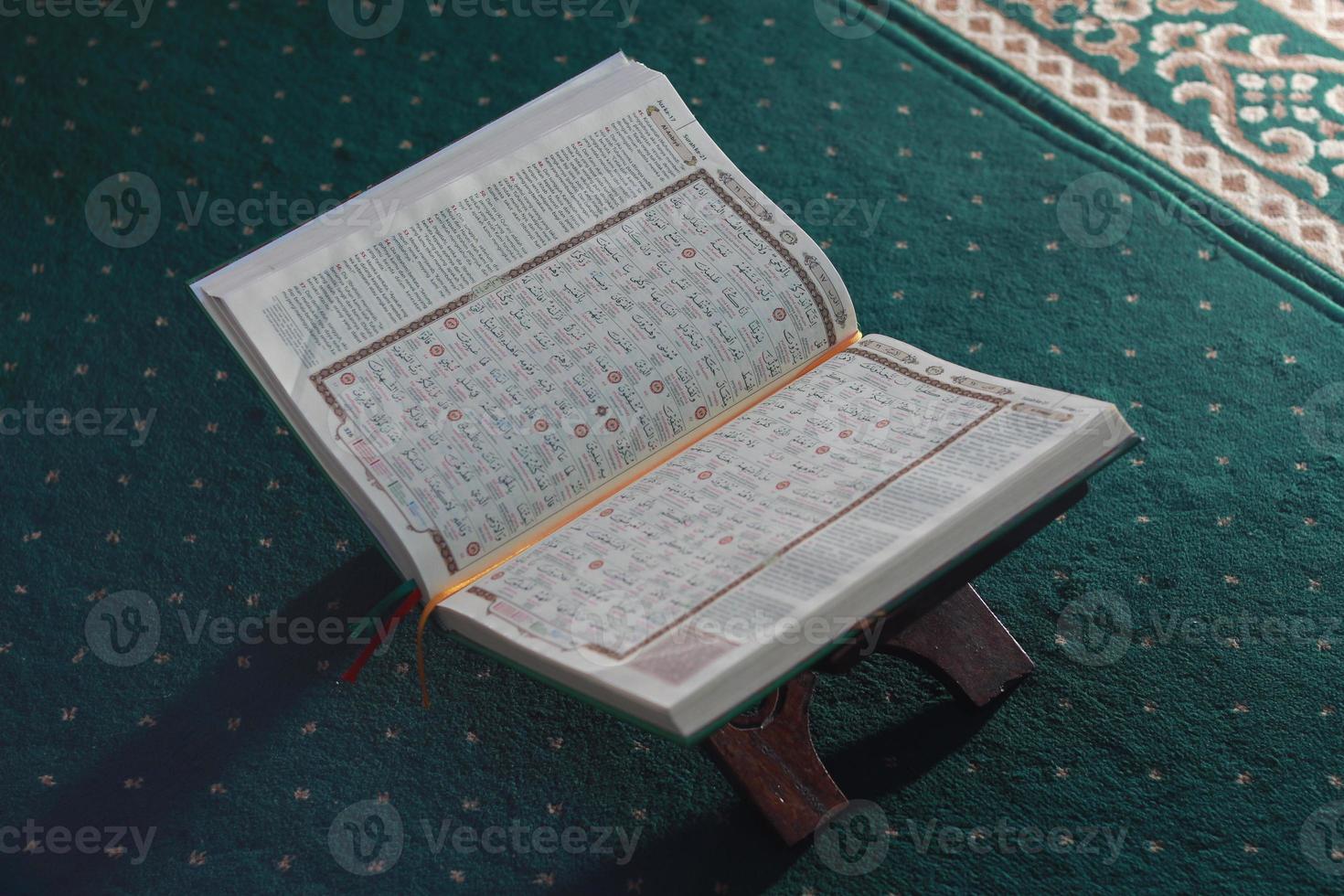 a close up of the holy book Al-Quran on a green prayer rug. Islamic photo concept.