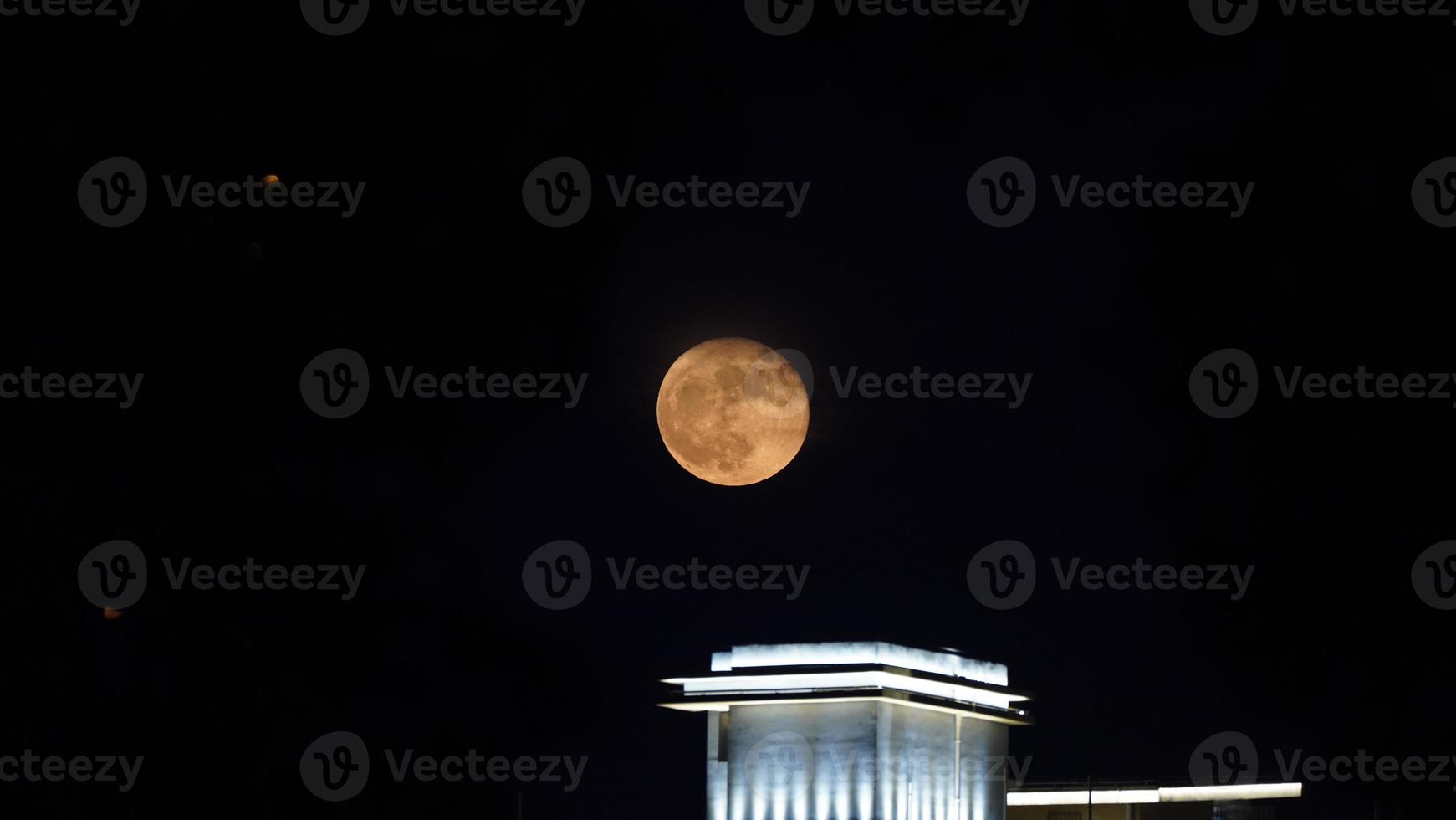 The moon just rising up in the city at night photo