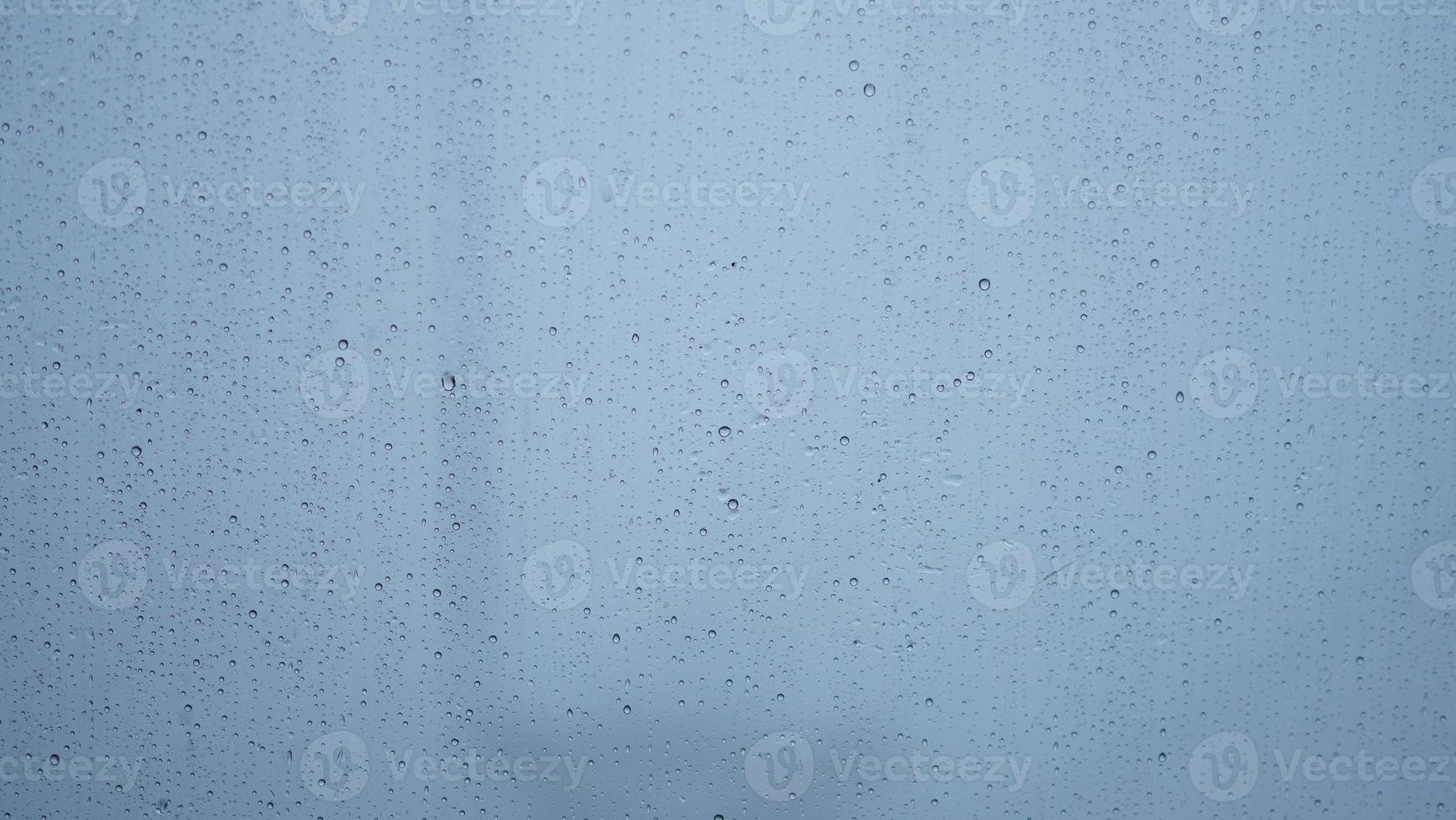 The rain droplets on the transparent glass window in the rainy day photo