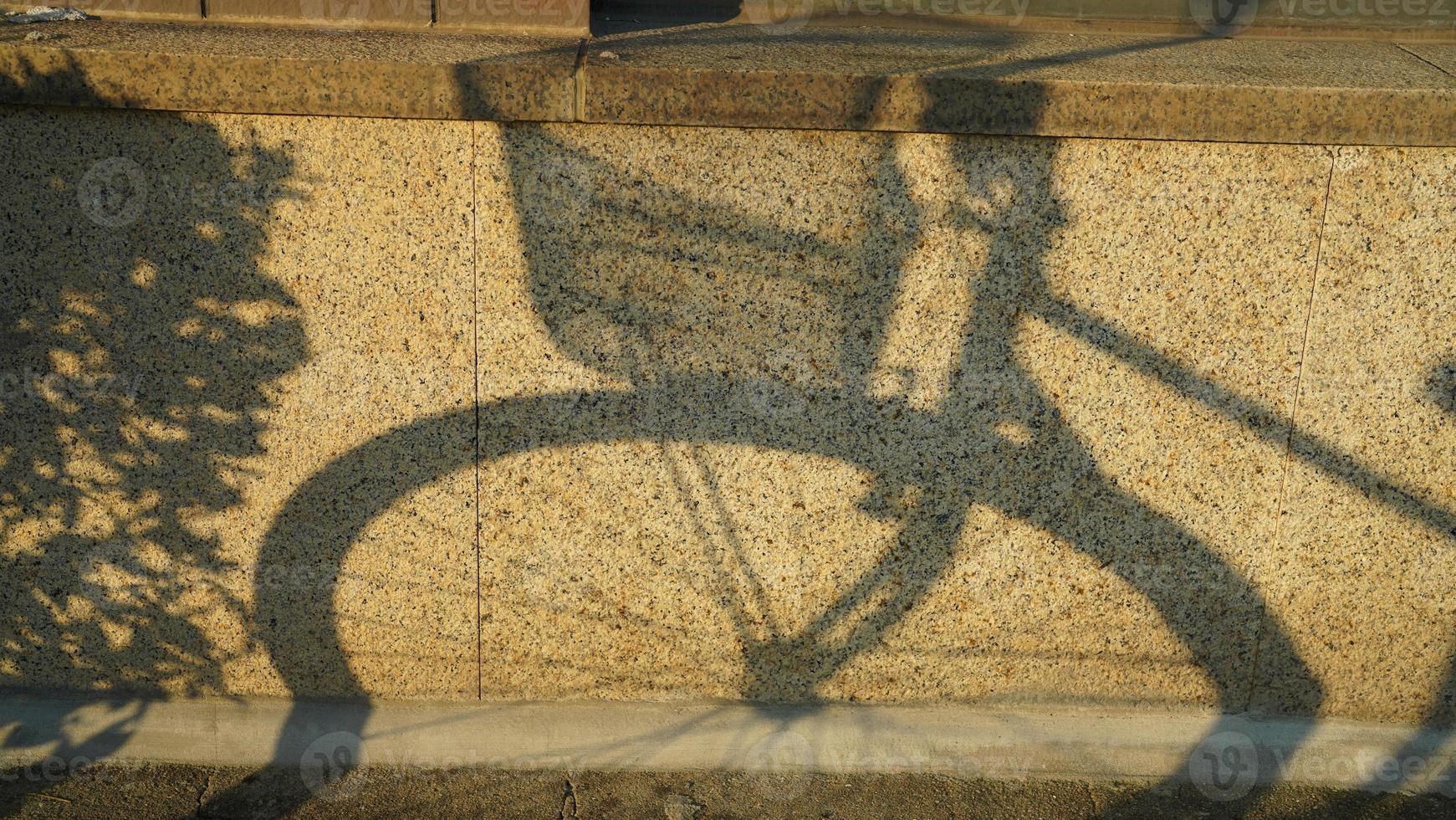 el bicicleta sombra en el pared por el calentar tarde luz de sol foto