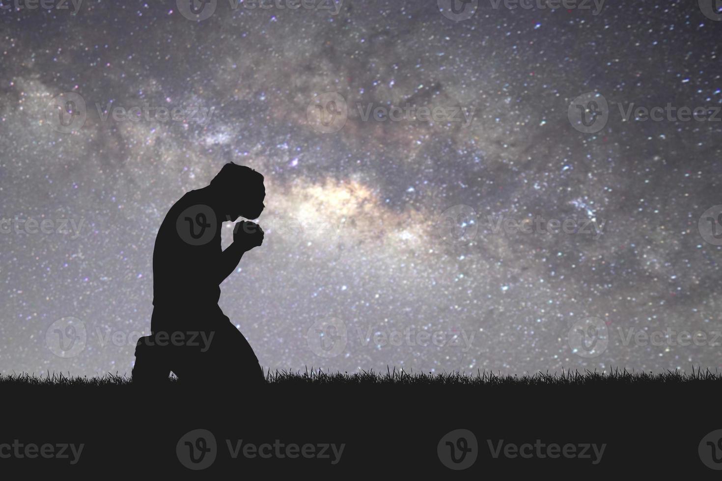 Man silhouette kneeling praying to god hopefully with the beautiful Milky Way photo