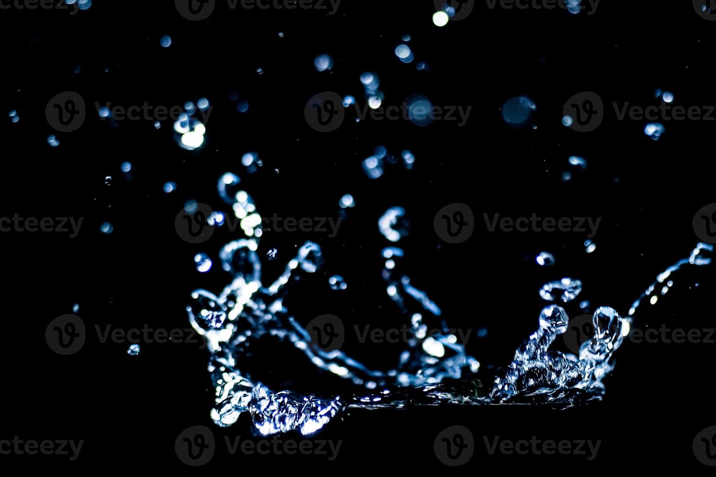 Splashing water on a black background. water droplets scattered on a black background photo