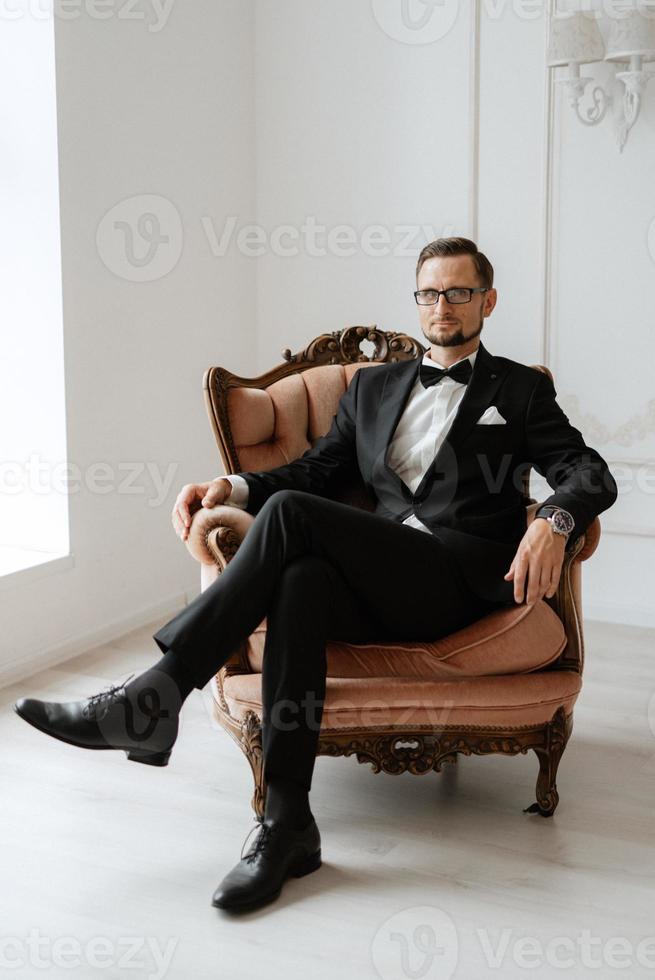 portrait of a groom in a black suit and glasses in a studio photo