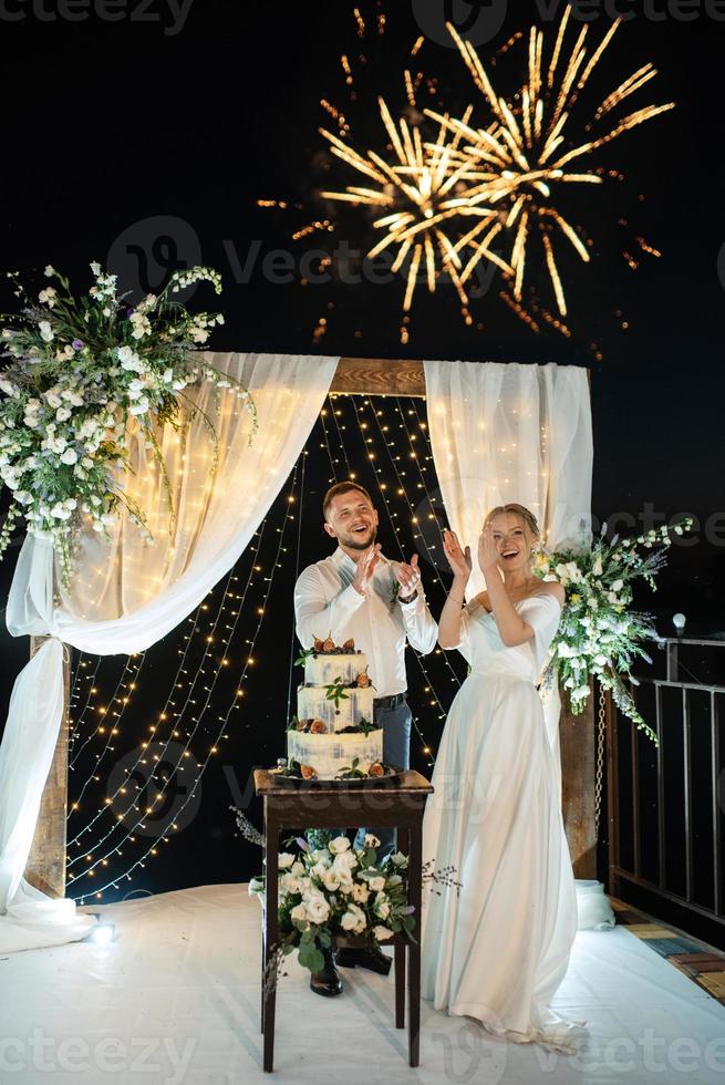 los recién casados felizmente cortan y prueban el pastel de bodas foto