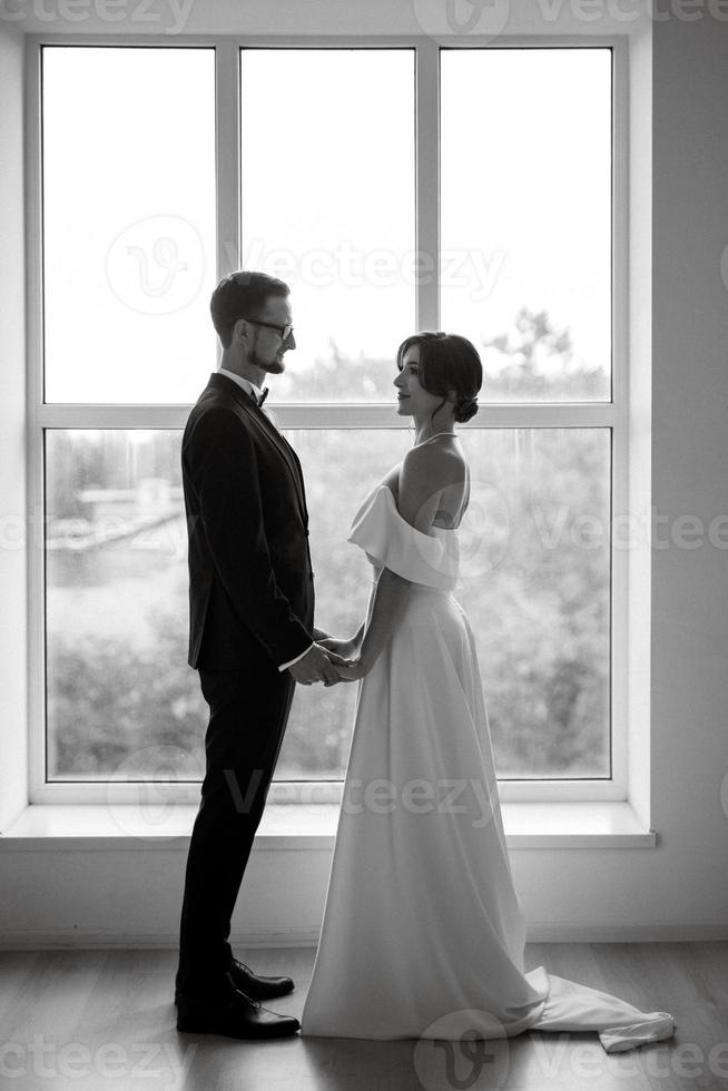 groom in a black suit tie and the bride in a bright studio photo