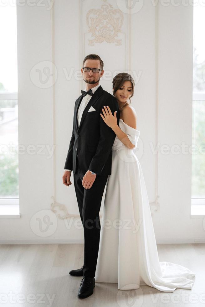 groom in a black suit tie and the bride in a bright studio photo
