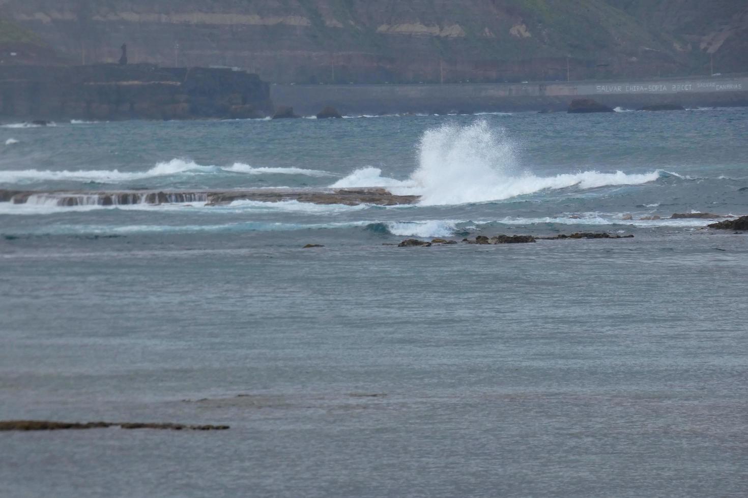 Large waves crashing against the rocks in the ocean photo