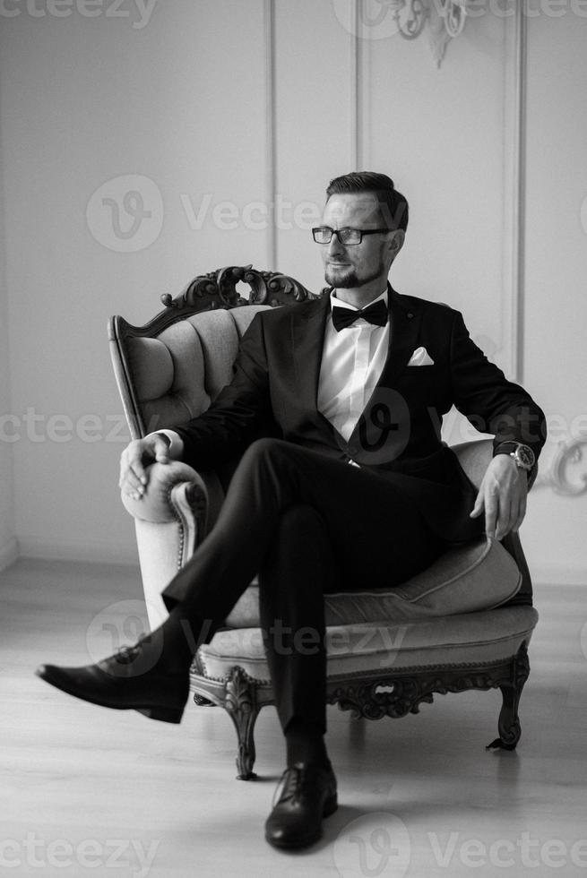 portrait of a groom in a black suit and glasses in a studio photo