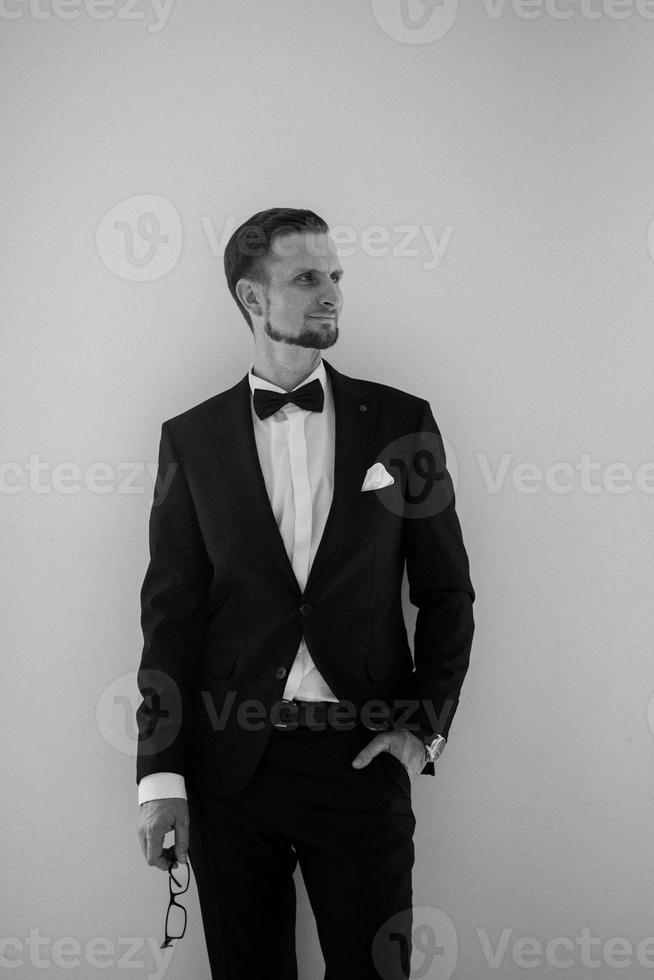 groom in a black suit with a bow photo