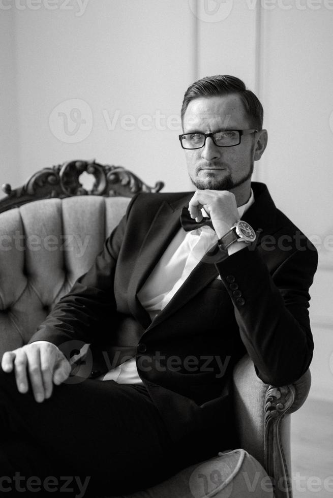 retrato de un novio en un negro traje y lentes en un estudio foto