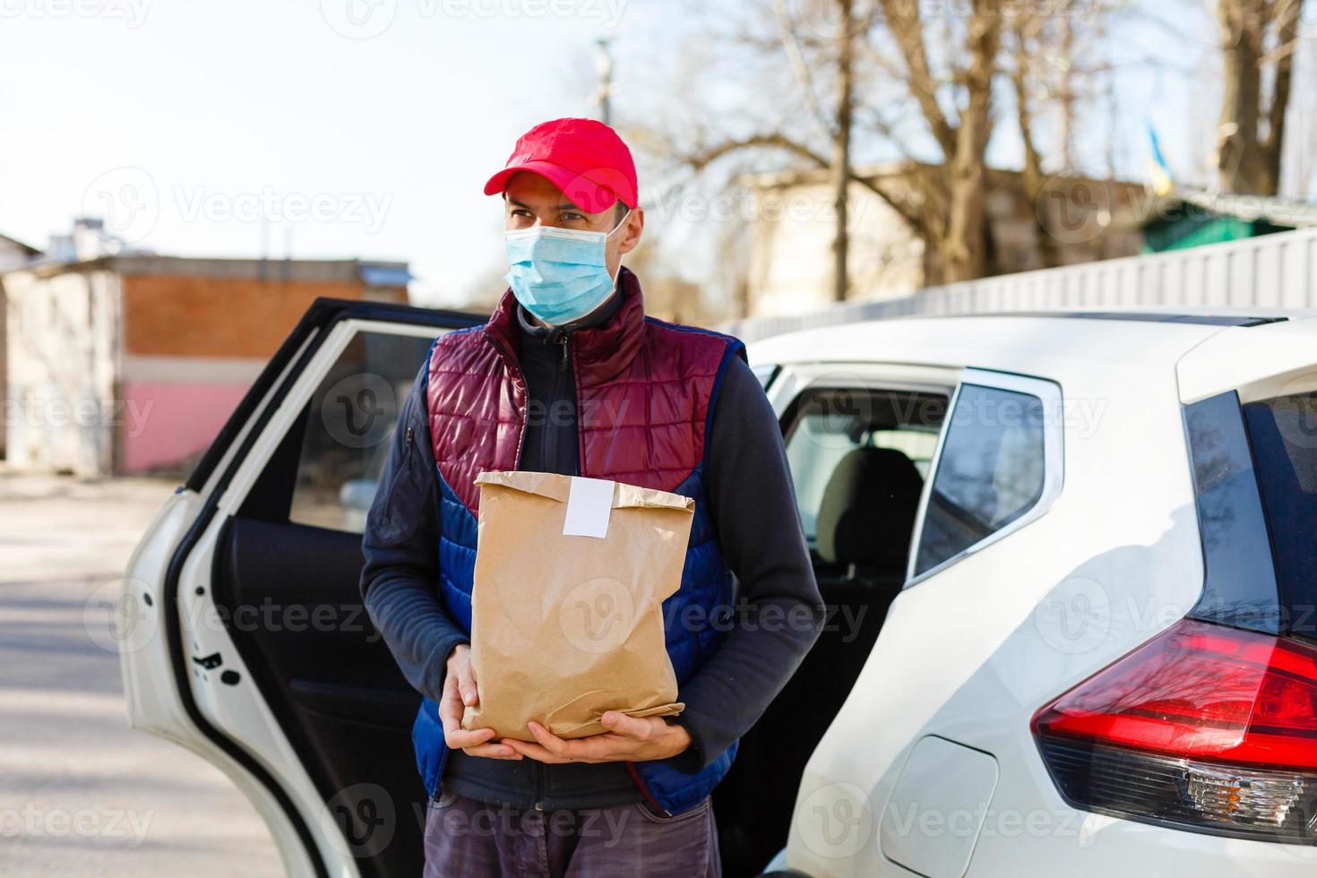 Courier in protective mask and medical gloves delivers takeaway food. Delivery service under quarantine, disease outbreak, coronavirus covid-19 pandemic conditions. photo