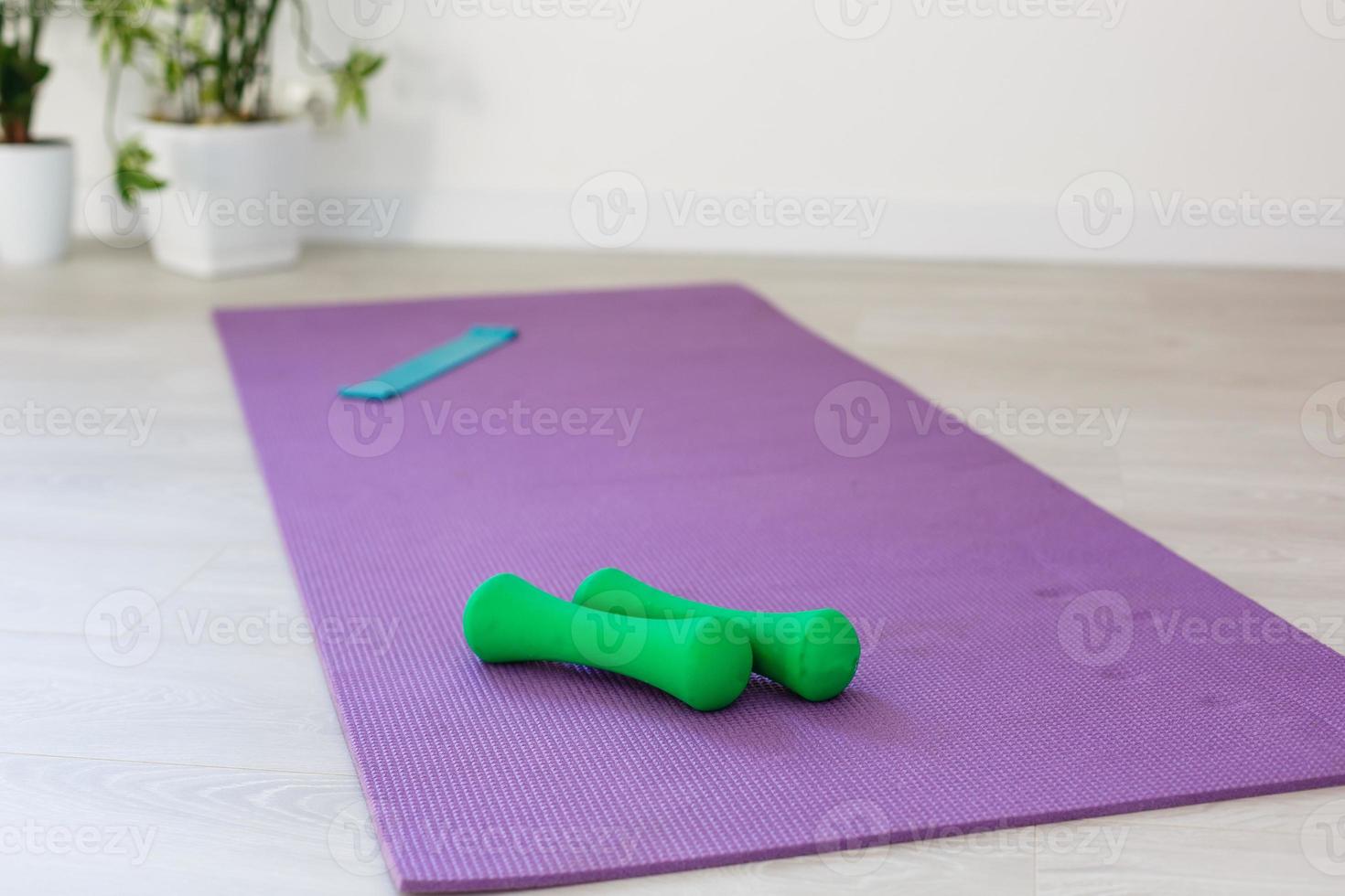 Unrolled yoga mat on wooden floor in modern fitness center or at home with big windows and white brick walls, comfortable space for doing sport exercises, meditating, yoga equipment photo