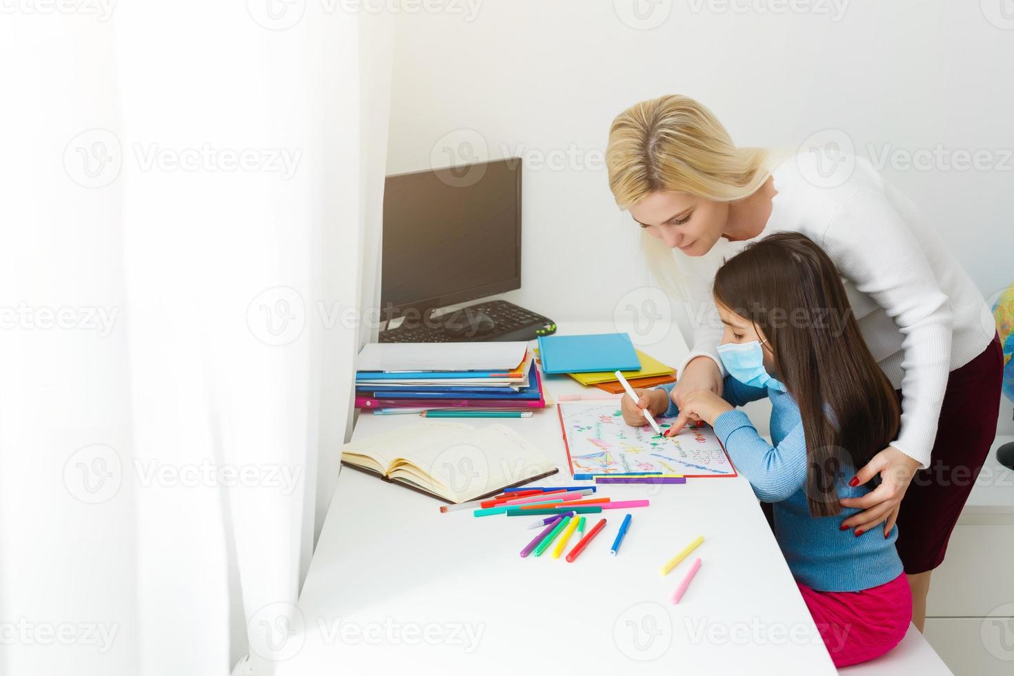 mother and daughter in protective mask do homework at distance home schooling, quarantine photo