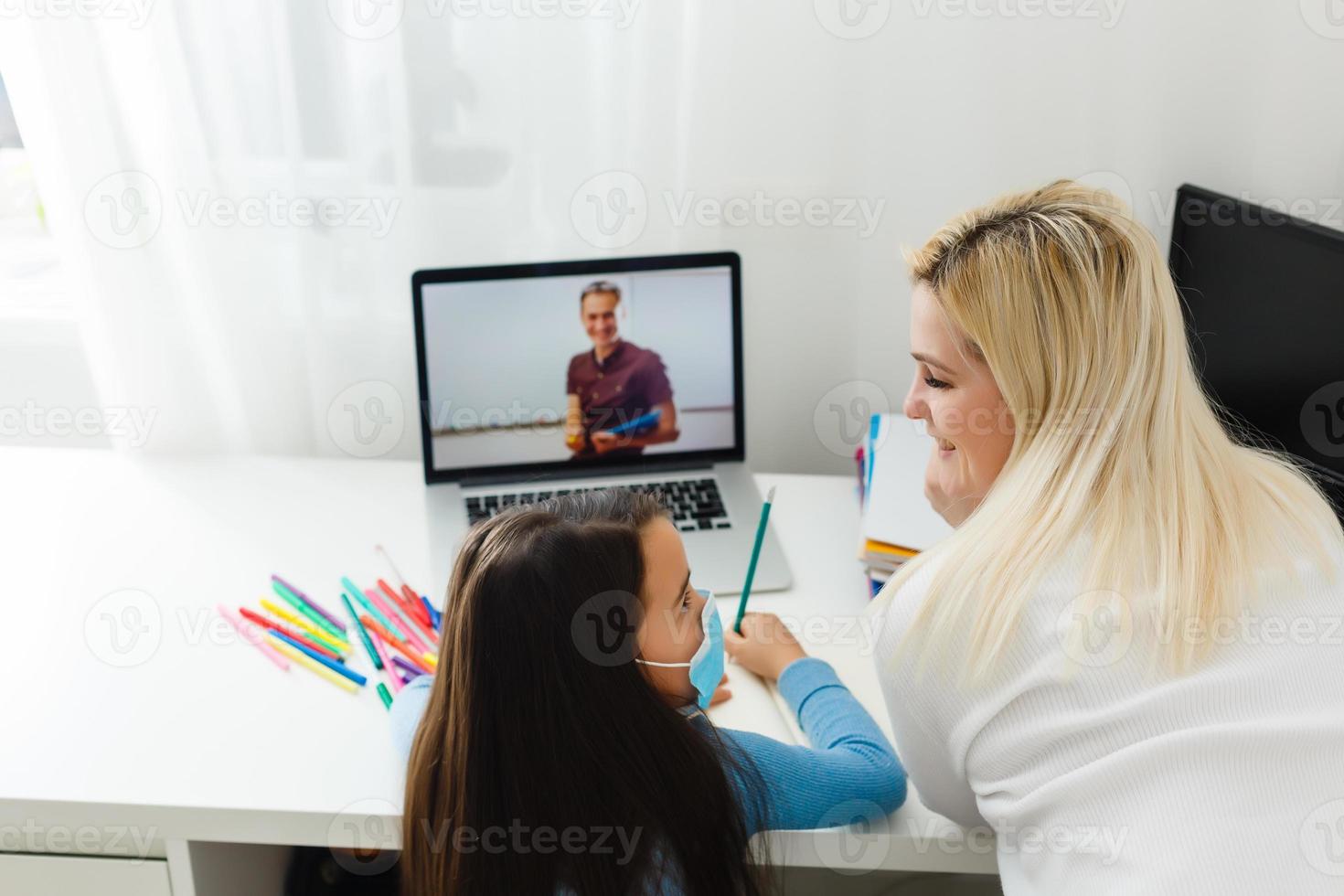 Digital technology education concept. little girl in a protective mask at distance home schooling, quarantine photo