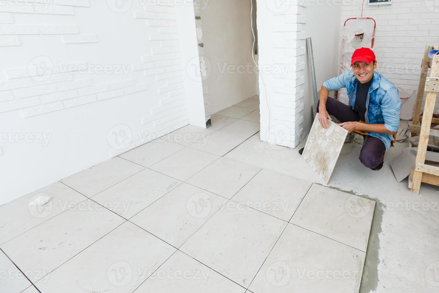 master is installing floor ceramic tile in a room, pressing down and leveling, interior finishing of premises of a living houses photo
