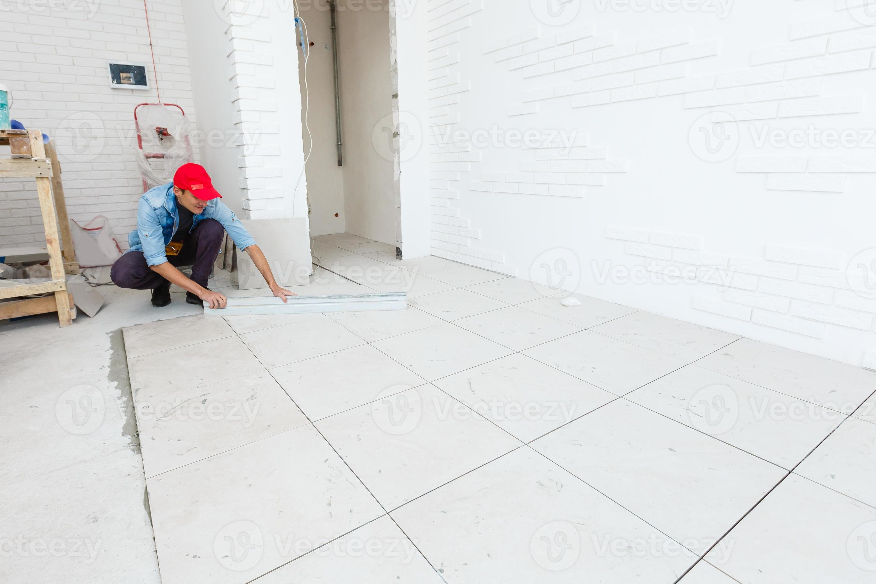 The master puts ceramic tiles on the floor 21544988 Stock Photo at Vecteezy