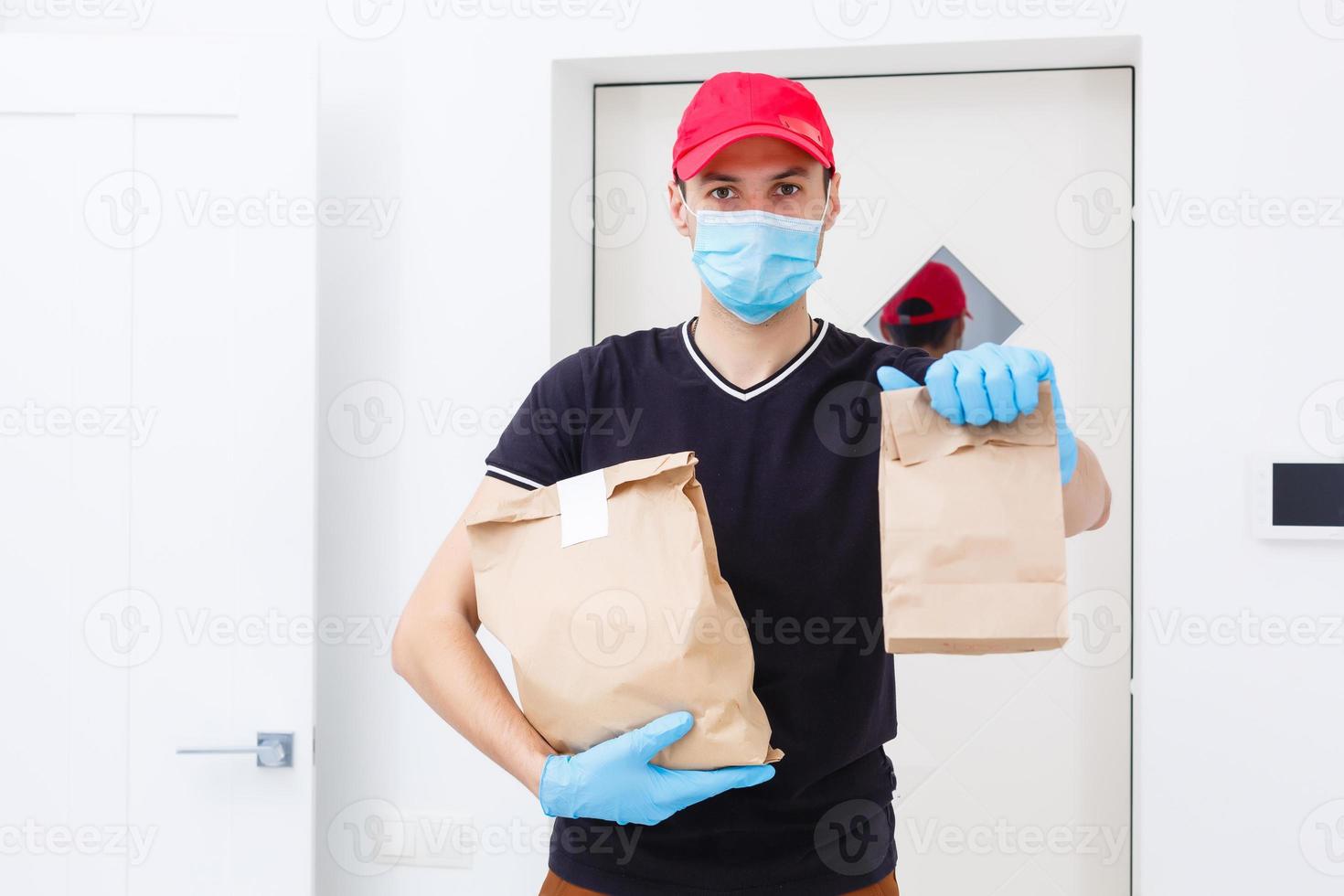 Delivery man holding paper bag with food on white background, food delivery man in protective mask photo