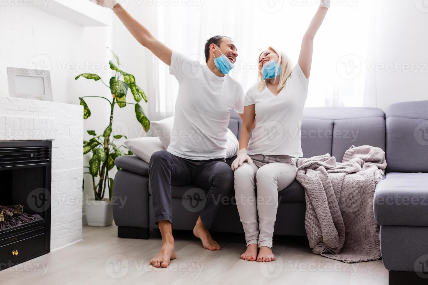 A young couple is sitting at home on self-quarantine. Husband and wife quarantined coronavirus in protective masks. New reality. Normal life in isolation. Read a book together. Italy europe covid-19 photo