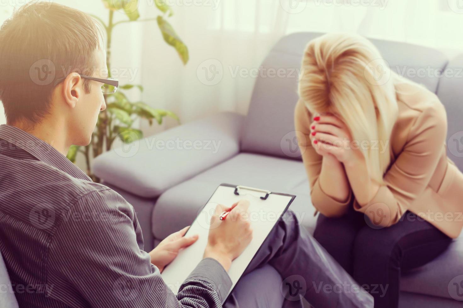 Psychologist talking to a depressed female patient in a room photo